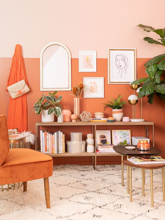 A Chic Modern Living Room With A Color Block Pink And Orange Accent Wall An Open Storage Unit Some Coffee Tables And An Orange Chair 