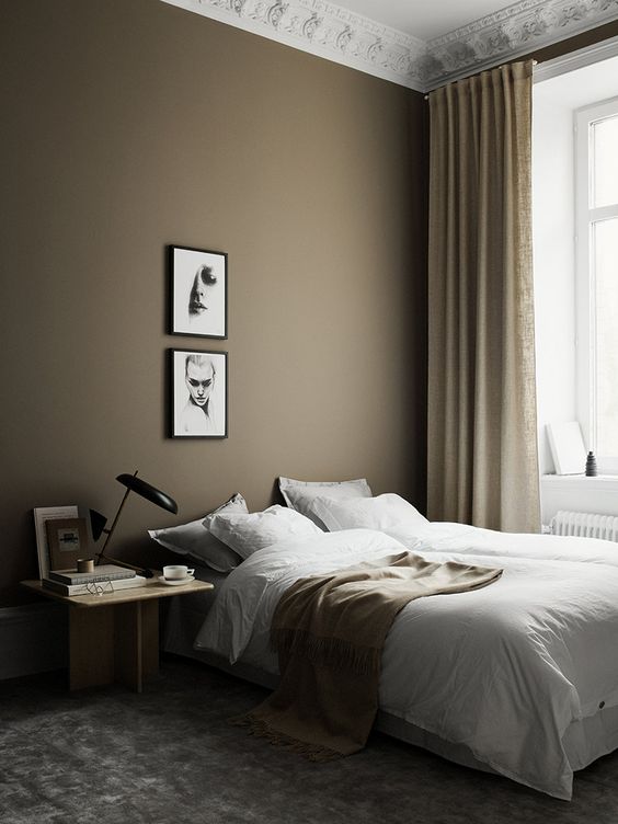 غرفة نوم إسكندنافية جميلة مع جدار لهجة رمادي داكن ، وسرير ، ومنضدة ملطخة بالضوء ، وجدار معرض صغير ولمسات ذهبية وذهبية