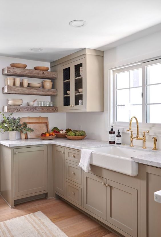 A Chic Taupe Farmhouse Kitchen With Shaker Cabinets Open Shelves White Stone Countertops And A Backsplash And Gold Fixtures Is Amazing 