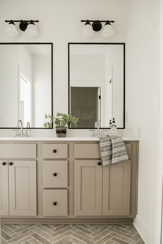 A Stylish Bathroom With A Grey Chevron Tile Floor A Taupe Double Vanity Two Mirrors Sconces And A Potted Plant Is A Very Chic Idea 