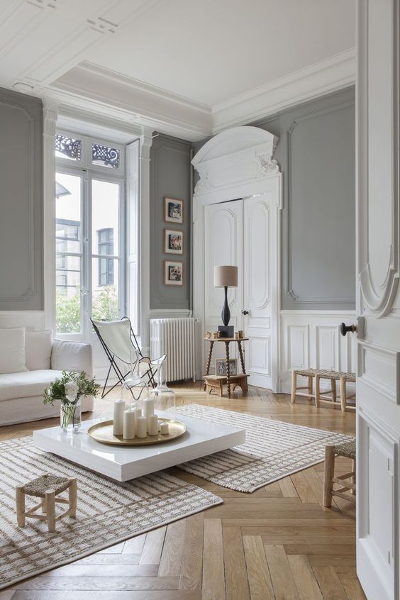 مساحة باريسية محايدة تخطف الأبصار بجدران رمادية ، ونسيج خشبي أبيض ، وتشكيل التاج ، وأثاث أبيض ومقاعد ومقاعد ذات ألوان محايدة