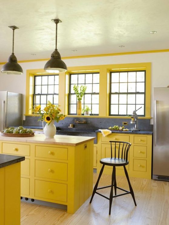 مطبخ مزرعة مشرق مع خزائن صفراء جريئة وإطارات نوافذ وأسطح من الحجر الرمادي ومغسلة كبيرة
