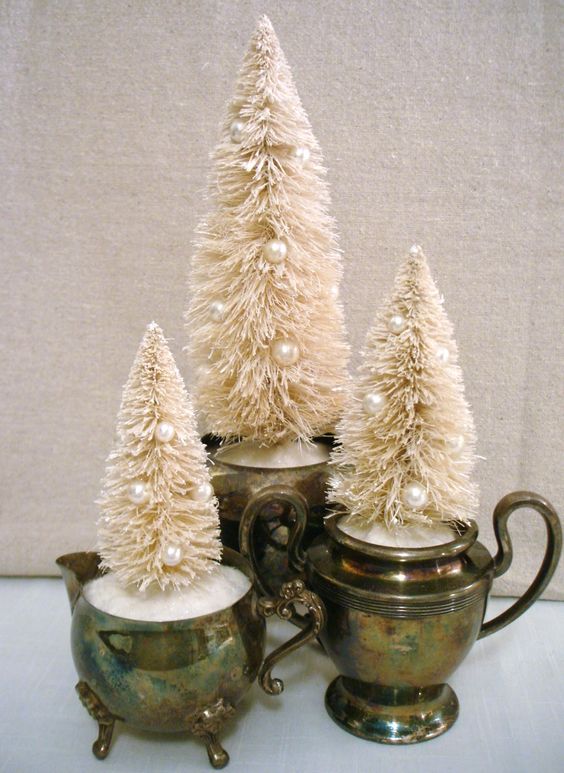 أدوات مائدة عتيقة مع ثلج زائف وفرشاة زجاجة بيضاء ، أشجار عيد الميلاد المزينة باللآلئ تشكل ديكورًا رائعًا للعطلات