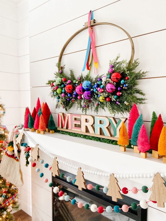 https://www.digsdigs.com/photos/2021/12/19-an-extra-bold-Christmas-mantel-with-bright-bottle-brush-trees-letters-a-wreath-with-ornaments-and-greenery-felt-balls-and-wooden-Christmas-trees.jpg