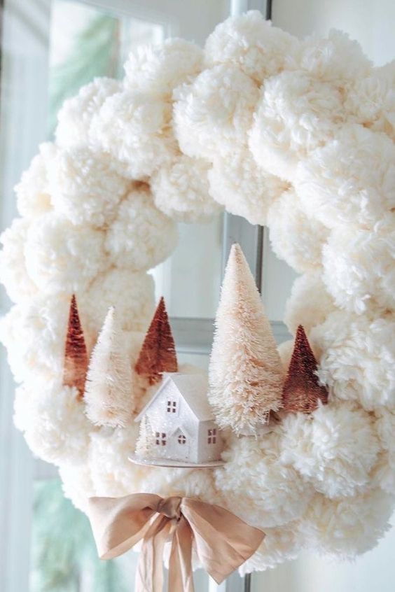 https://www.digsdigs.com/photos/2021/12/27-a-delicate-white-pompom-Christmas-wreath-with-blush-and-rustic-bottle-brush-trees-and-a-mini-house-plus-a-mauve-bow.jpg
