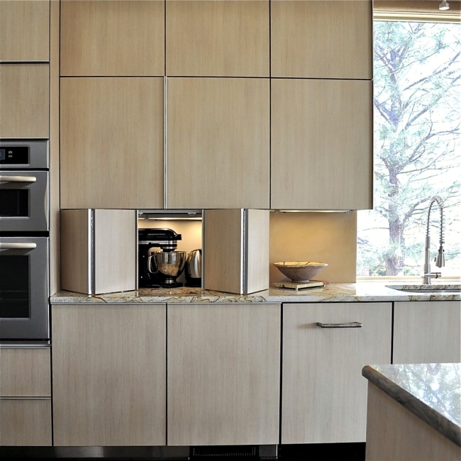 مطبخ عصري أنيق مع خزانات سفلية تتميز بأبواب ثنائية الطي وأضواء بالداخل لإخفاء الأجهزة