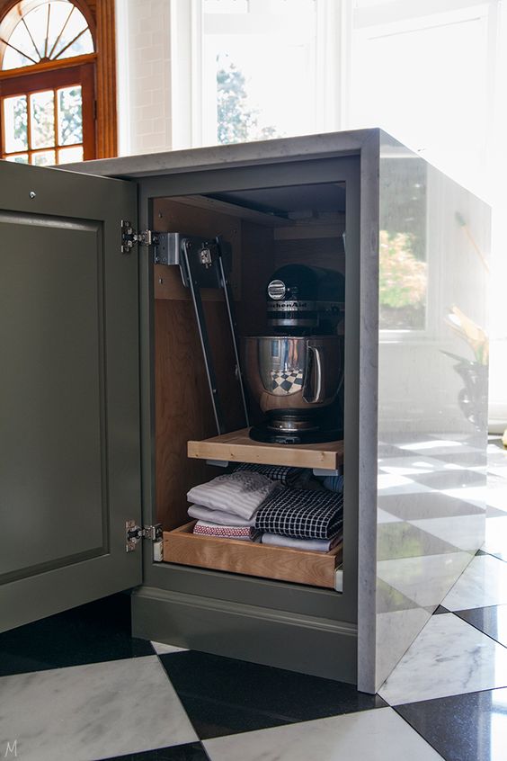 خزانة مطبخ صغيرة وضيقة مع أرفف قابلة للسحب والرفع تحتوي على أدوات المطبخ ومناشف المطبخ