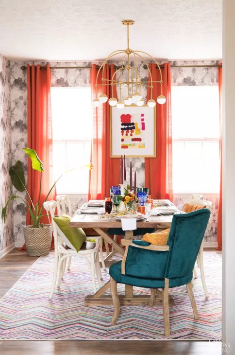 مساحة طعام ملونة مع ورق حائط مطبوع وطاولة خشبية وكراسي غير متطابقة وستائر coquelicot ولمسات متطابقة على الطاولة