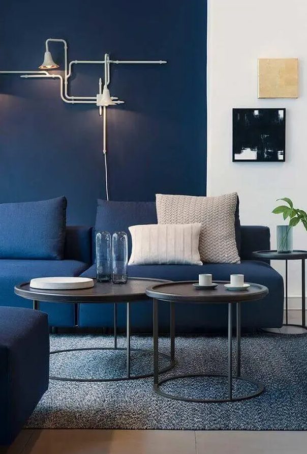 كنب عصري باللون الازرق A-bright-modern-living-room-with-navy-walls-navy-sofas-black-side-tables-and-cool-art-unique-industrial-inspired-sconces