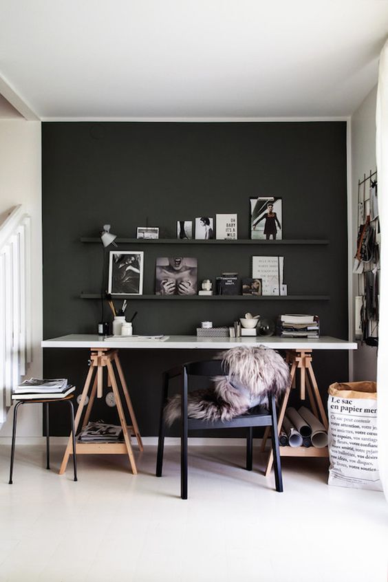 A Moody Home Office With A Black Accent Wall A Trestle Deck A Black Chair And A Stool A Ledge Gallery Wall And A Grid Memo Board 