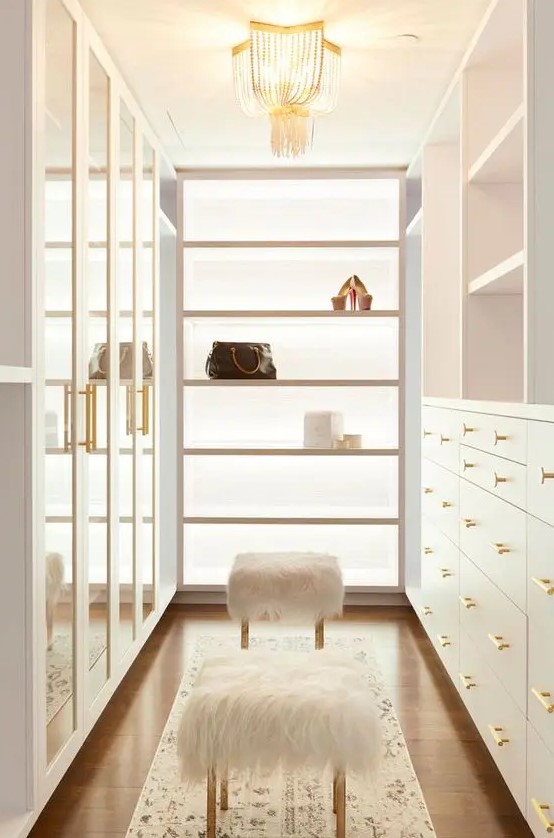 https://www.digsdigs.com/photos/2022/11/a-neutral-and-very-chic-closet-with-drawers-with-glass-doors-open-shelves-and-drawers-open-shelves-and-faux-fur-stools-plus-a-crystal-chandelier.jpg