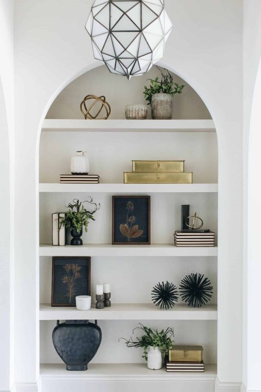 https://www.digsdigs.com/photos/2023/01/04-a-large-arched-niche-with-shelves-and-lots-of-stuff-on-display-books-plants-vases-and-candles-is-a-cool-idea.jpg