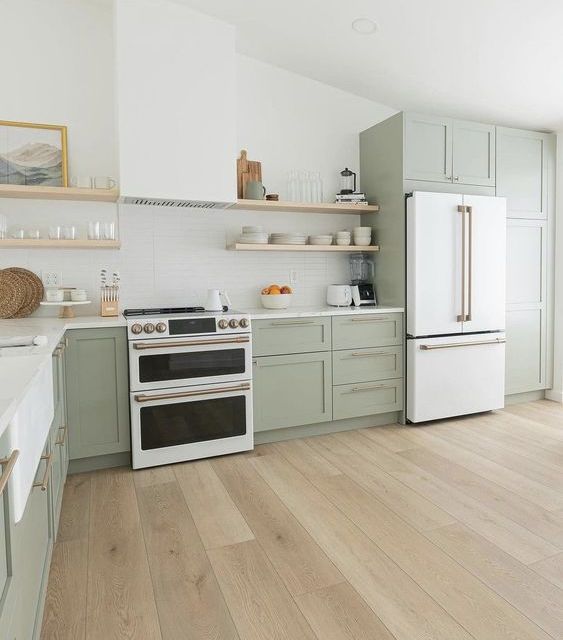 https://www.digsdigs.com/photos/2023/02/a-beautiful-sage-green-farmhouse-kitchen-with-shaker-cabinets-open-shelves-a-hood-a-white-cooker-and-brass-fixtures.jpg