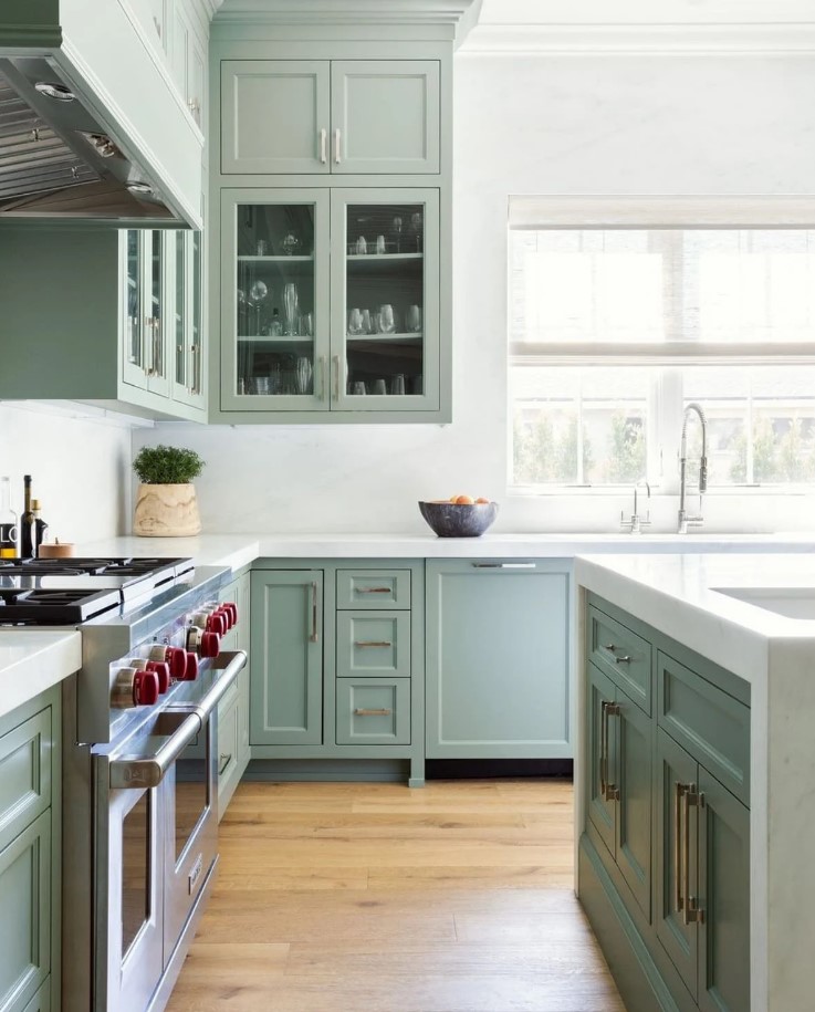 A Beautiful Sage Green Kitchen With Shaker And Glass Front Cabinets White Stone Countertops And A Backsplash Feels Airy 