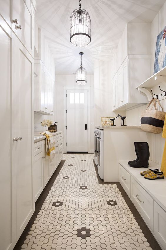 a creamy laundry mudroom with shaker cabinets, a hex tile floor, a bench with storage, a washing machine and a dryer and pendant lamps