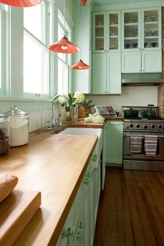 https://www.digsdigs.com/photos/2023/03/a-vintage-inspired-mint-green-kitchen-with-butcherblock-countertops-pink-pendant-lamps-and-a-white-beadboard-backsplash.jpg