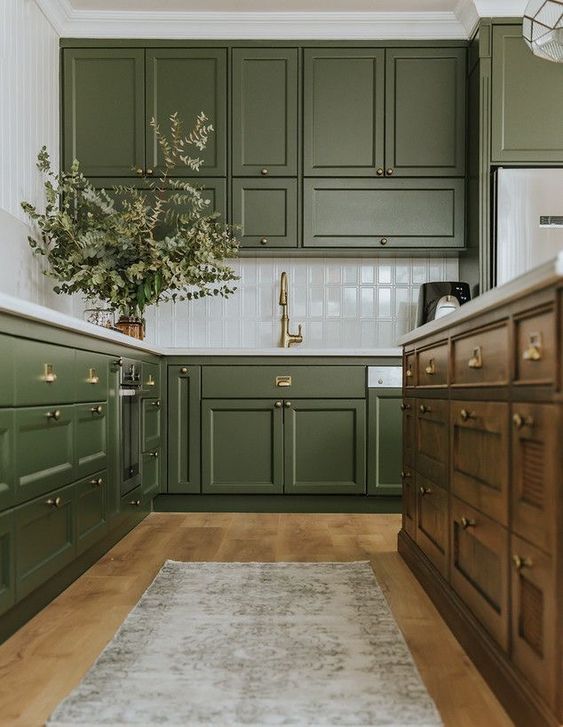 A Chic Olive Green Farmhouse Kitchen With Shaker Cabinets A White Tile Backsplash A Dark Stained Kitchen Island And A Printed Rug 