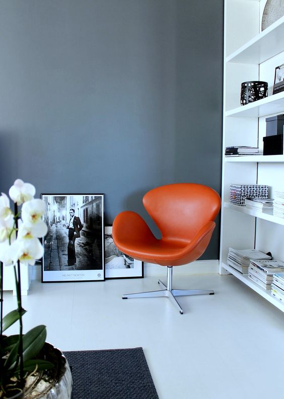 https://www.digsdigs.com/photos/2023/05/a-black-and-white-Scandinavian-space-with-a-large-bookcase-an-orange-Swan-chair-black-and-white-artwork-and-a-potted-plant.jpg