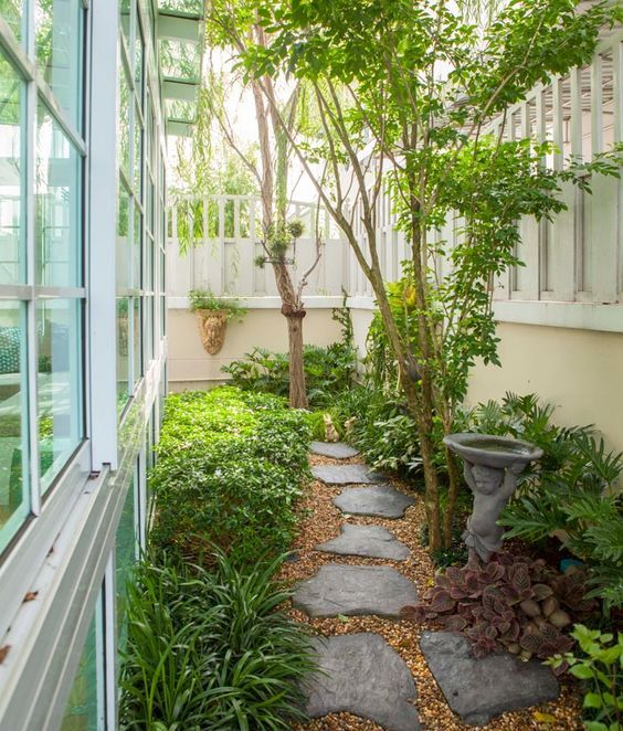 a zen-like side yard with an irregular stone path, greenery, a vintage bird bath and some trees