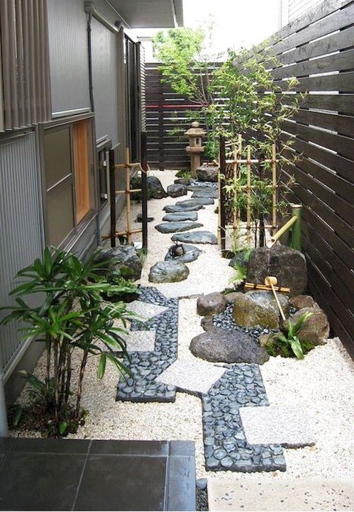 a fantastic Japanese garden with a catchy pathway, bamboo fences and greenery and a stone lantern in the corner of the garden