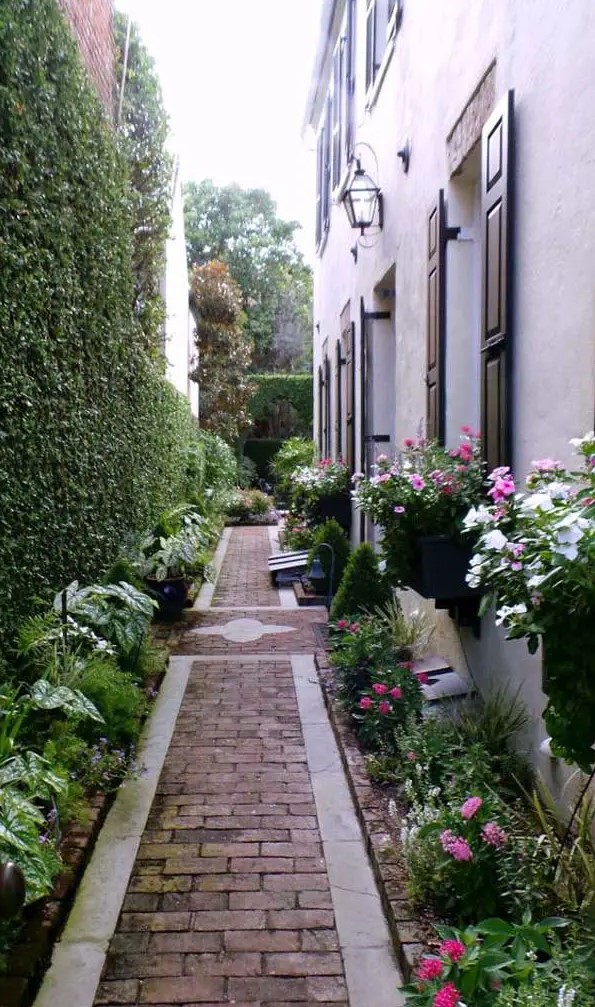 a beautiful and elegant floral walkway with a brick path, a living wall and lots of greenery and blooms around