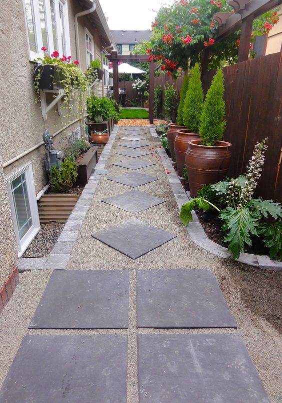 a chic side yard with pavements, potted greenery and lots of blooms to spruce up the space with color