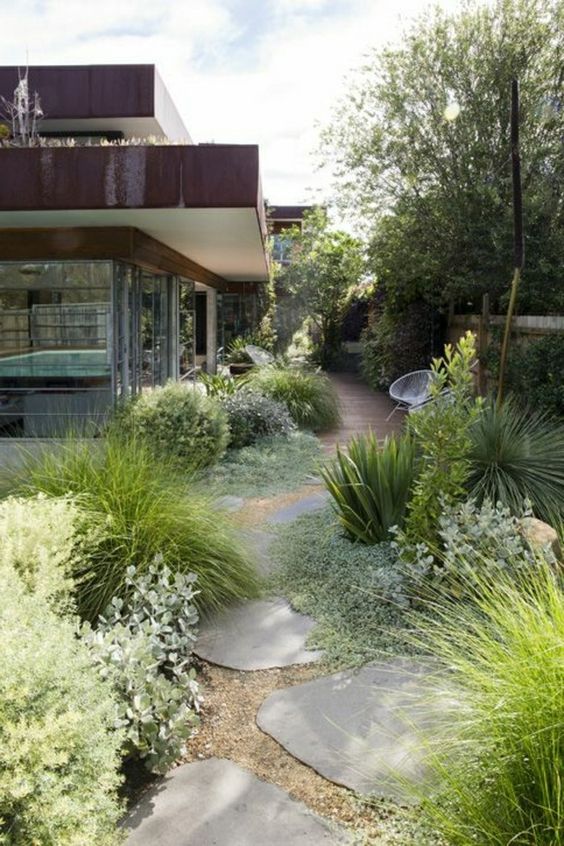 a cool and textural side yard with a wooden deck and irregular stone paths, lots of greenery and grasses for a catchy look