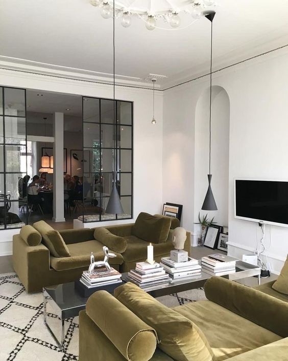 a bold and refined living room with a couple of soft green daybeds, a coffee table with book and pendant lamps