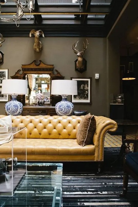 a sophisticated living room with a yellow leather Chesterfield sofa, taxidermy, plexiglass items and refined lamps