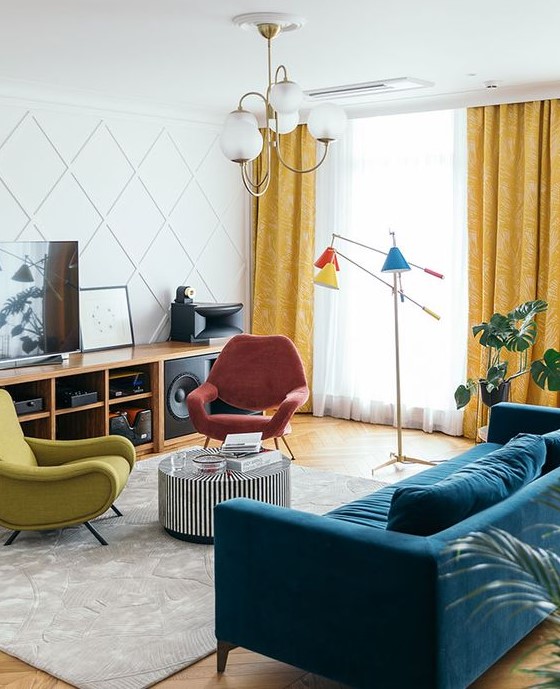 a bright mid-century modern living room with a stained storage unit, a coral and mustard chair, a navy sofa, a side table and colorful lamps