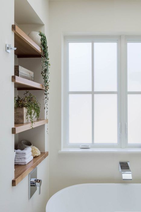 https://www.digsdigs.com/photos/2023/08/49-a-stylish-neutral-bathroom-with-a-niche-with-wooden-shelves-used-for-storing-stuff-and-potted-greenery-an-oval-tub.jpg