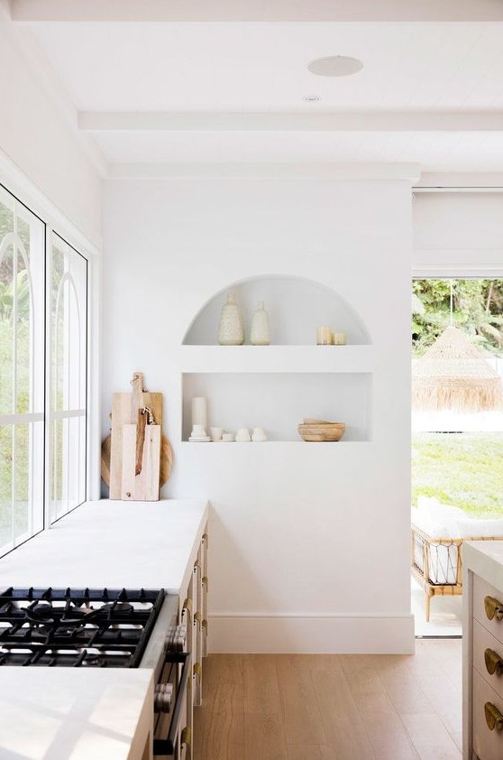 58 An Airy White Kitchen With An Arched Niche With Beautiful Tableware On Display Is A Chic And Lovely Space 