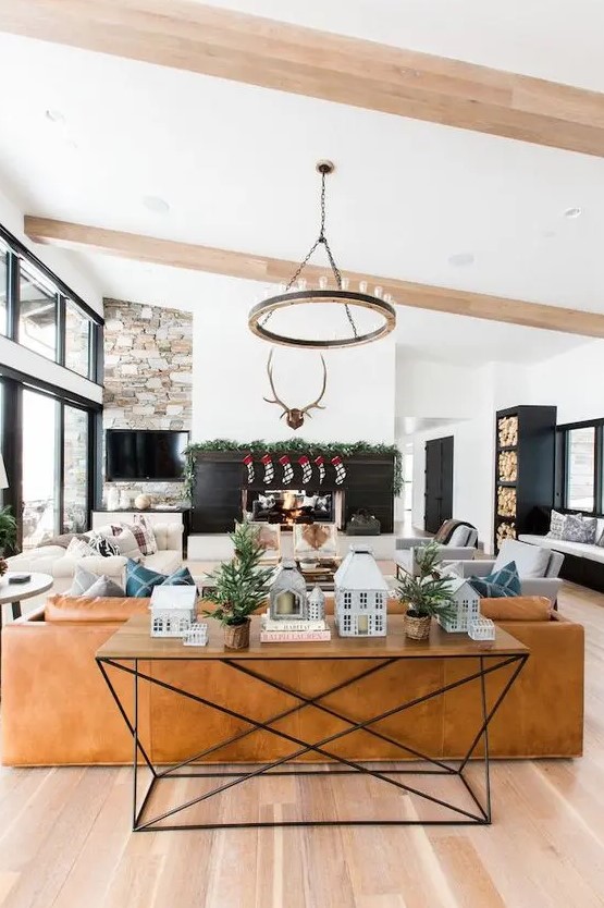 https://www.digsdigs.com/photos/2023/08/a-barn-living-room-with-a-fireplace-clad-with-black-planks-a-TV-on-a-stone-wall-a-leather-sofa-and-neutral-seating-furniture-a-round-chandelier.jpg