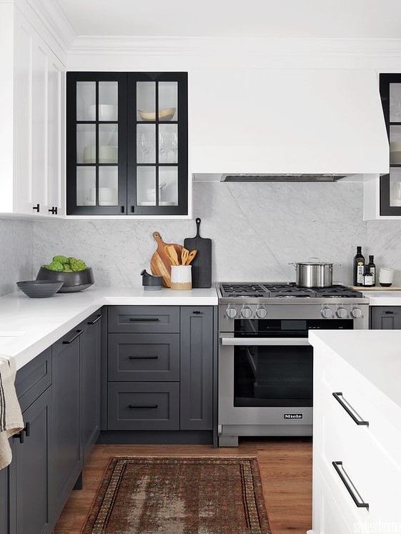 a beautiful two tone kitchen with grey and white shaker style cabinets, white quartz countertops and a backsplash plus a boho rug