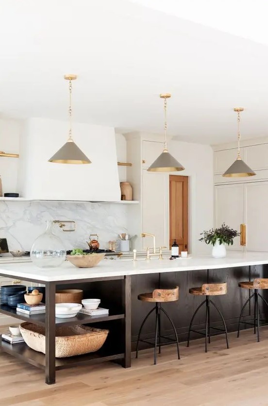 a chic farmhouse kitchen with white shaker style cabinets, a dark stained kitchen island with open shelves, grey pendant lamps