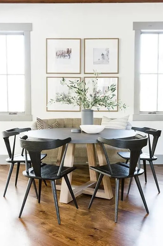 a chic modern farmhouse dining nook with a loveseat, a round table, black chairs, a chic gallery wall and greenery in a vase