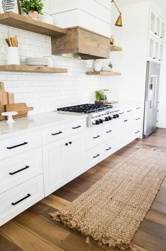 a cozy white modern farmhouse kitchen with a white subway tile backsplash, touches of natural wood and black fixtures