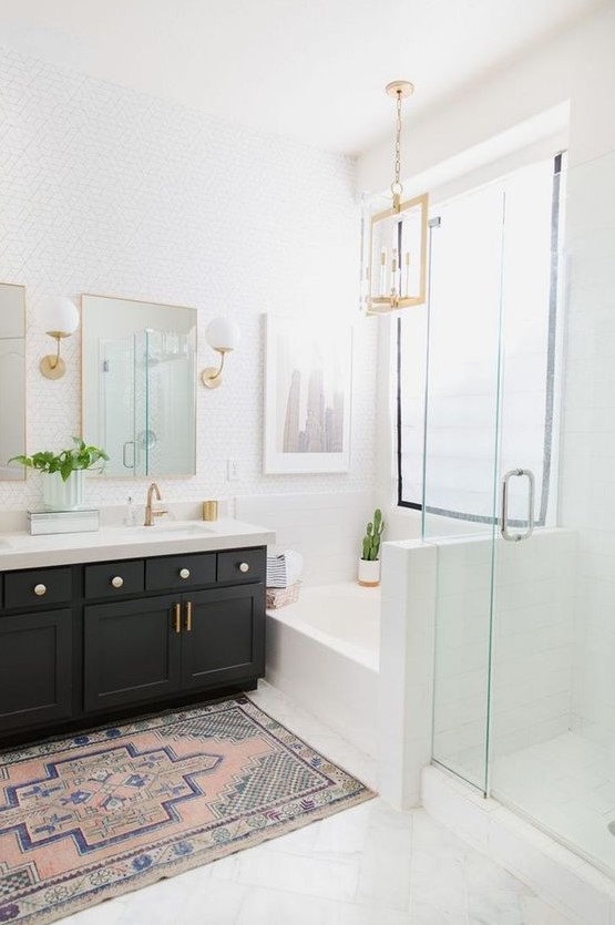 a light-filled farmhouse bathroom with a black vanity, gilded touches, white tiles and lamps