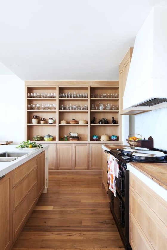 a light-stained wooden kitchen with wooden countertops, built-in wooden storage units and a white hood is very welcoming