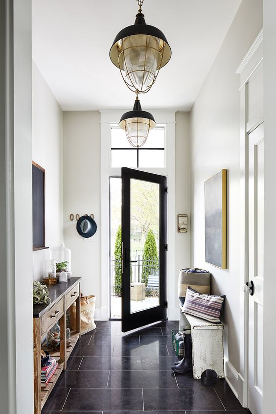 a lovely farmhouse entry with a white bench and pillows, a console table with some decor and lovely vintage pendant lamps