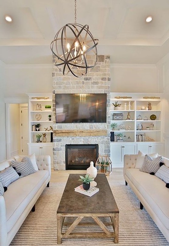 a lovely modern farmhouse living room with a brick clad fireplace, elegant sofas, a rustic coffee table and a sphere pendant lamp