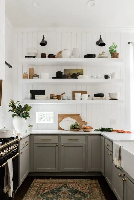 a modern English country kitchen with white planked walls, grey shaker style cabinets, open shelves, gold touches and potted plants