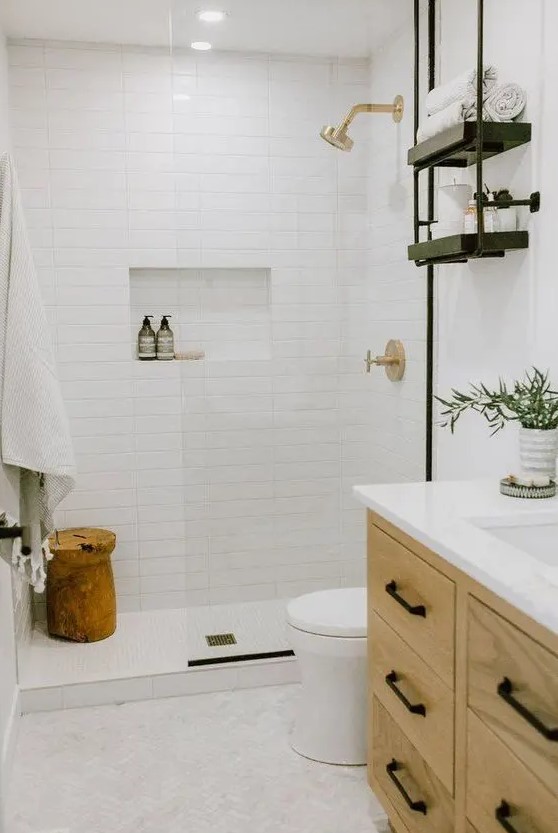 a modern country bathroom with white tiles, a light stained vanity, black and gold fixtures and open shelves is a chic space