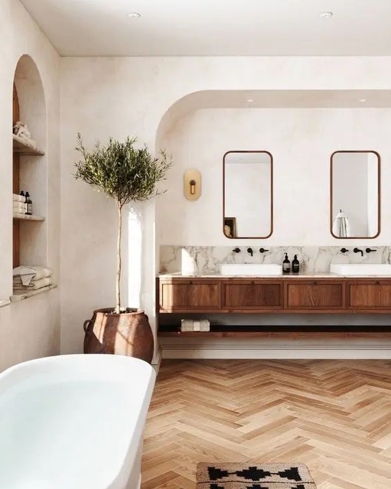 a modern country bathroom with white walls and a ceiling, a stained chevron floor, a stained vanity and arched niches is lovely