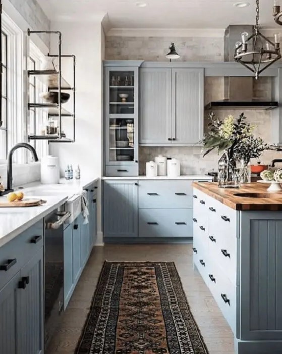 a modern country kitchen with light grey cabinets, butcherblock, white countertops, black fixtures and a vintage metal lamp