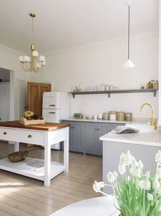 a modern country style kitchen with grey cabinets and a white kitchen island, pendant lamps and touches of gold