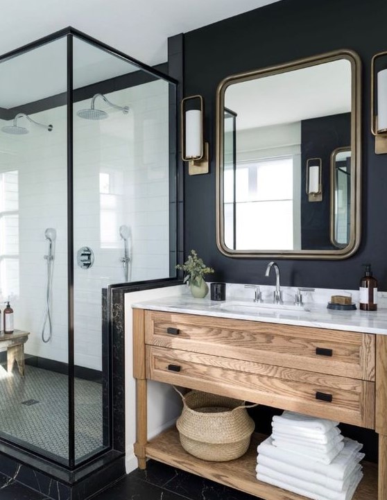 a modern farmhouse bathroom with a stained vanity, a mirror in a metal frame, a shower and black walls and floor