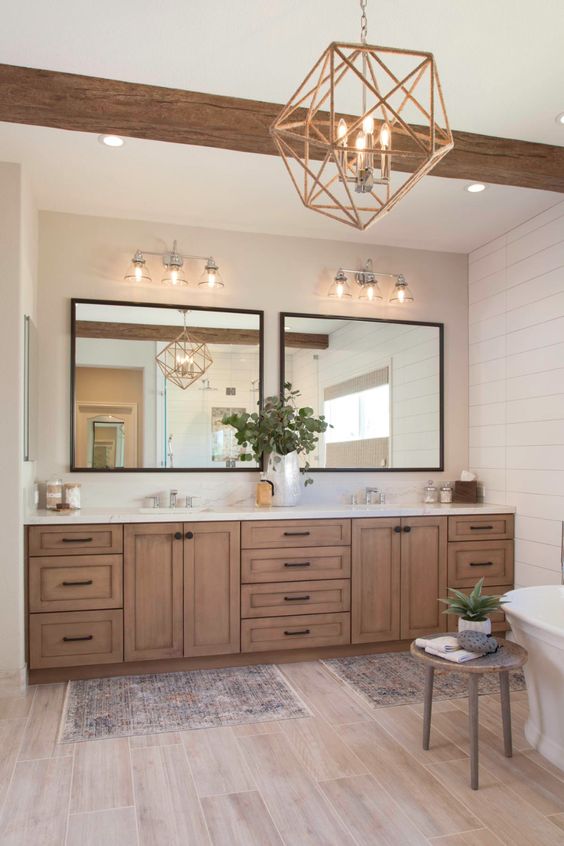 a modern farmhouse bathroom with wooden beams, shiplap walls, a double timber vanity, a tub, boho rugs, a geometric pendant lamp