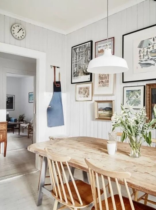 a modern farmhouse dining room with a chic wooden dining set, a gallery wall and simple white lamps