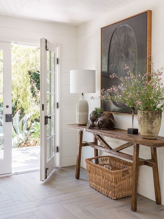 a modern farmhouse entry with a stained console, a basket, a table lamp, some art and blooms is gorgeous